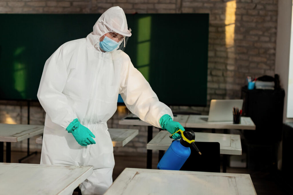 A technician in protective gear disinfecting a room as part of professional bedbug removal services.